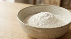 A bowl of mixed flour for a funfetti cake from scratch on a light oak wood table.